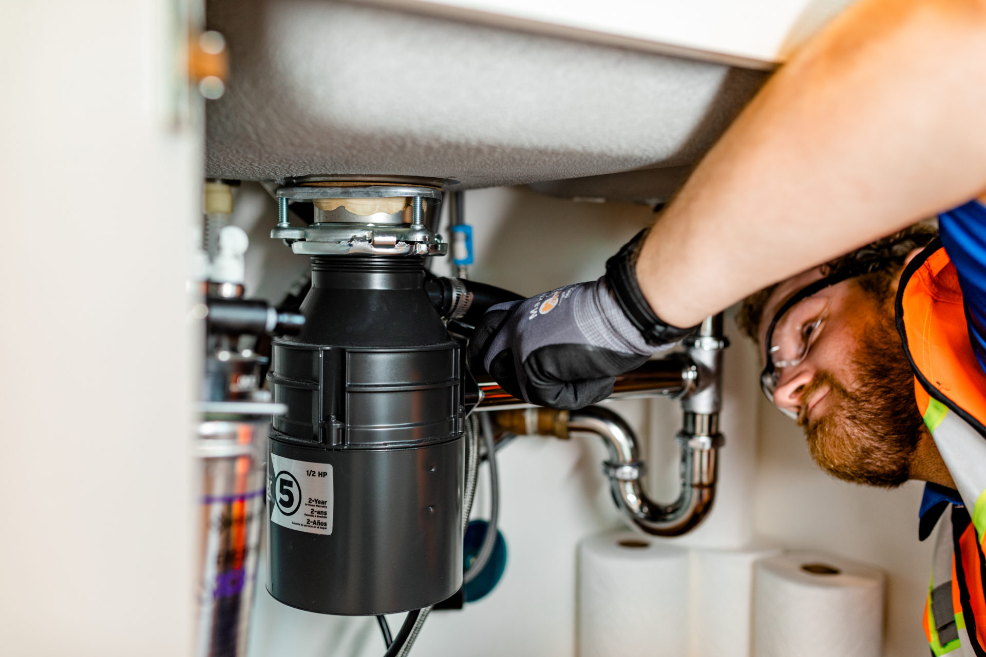 Swinerton Facility Solutions Employee Fixing Under Sink Plumbing